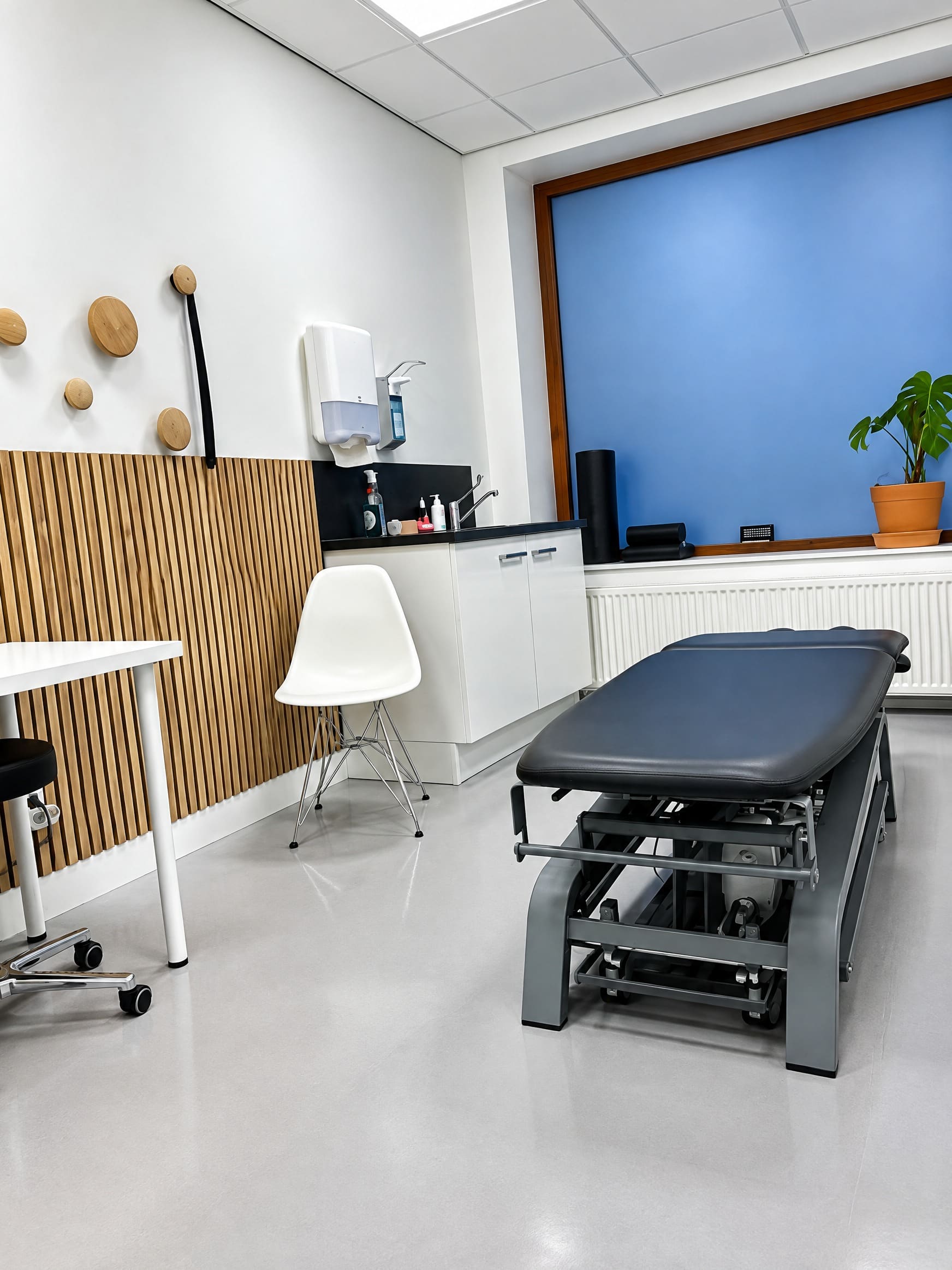 Een behandelkamer van Fysiotherapie Oort met behandelbank en houten lattenwand